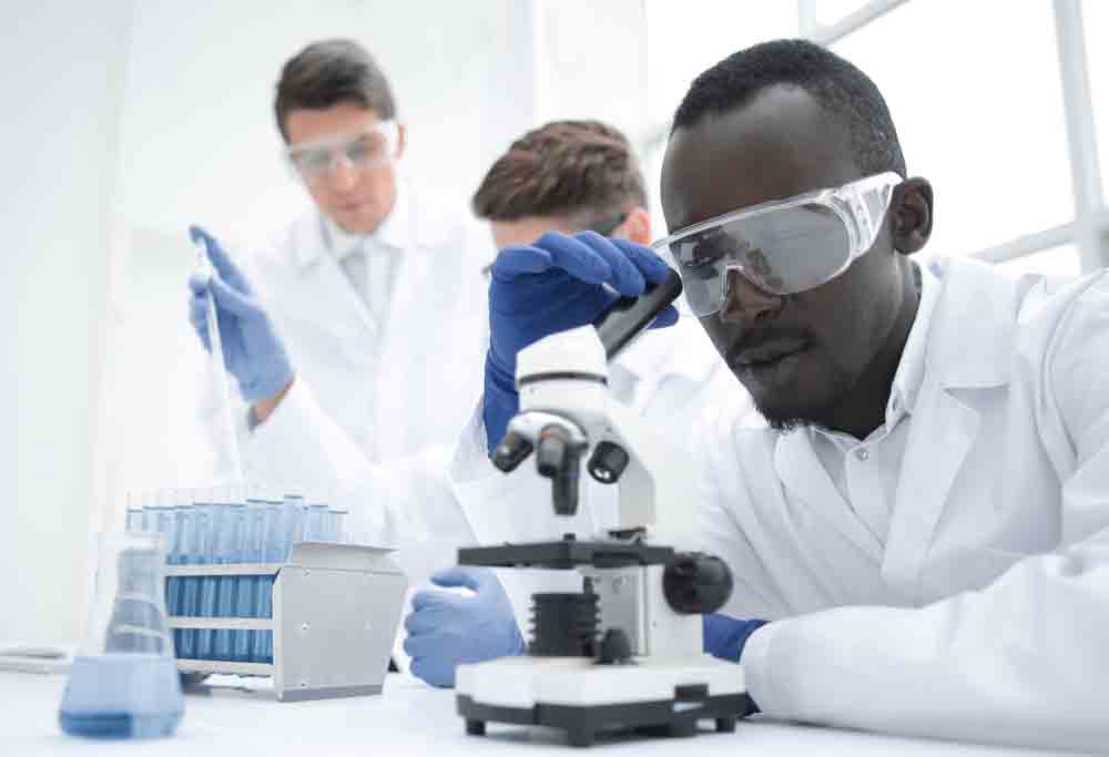 Lab technicians examining a sample at a microscope